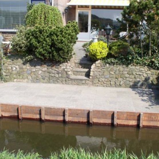 Strak stenen terras met houten beschoeiingen